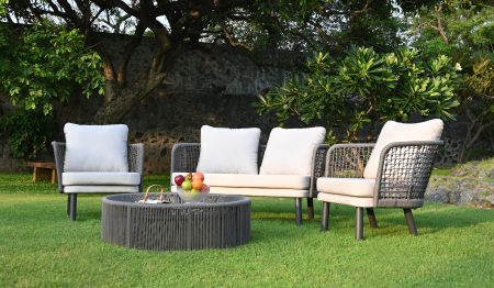 Monsoon outdoor furniture set with cushioned sofa, chairs, and round table on garden lawn.