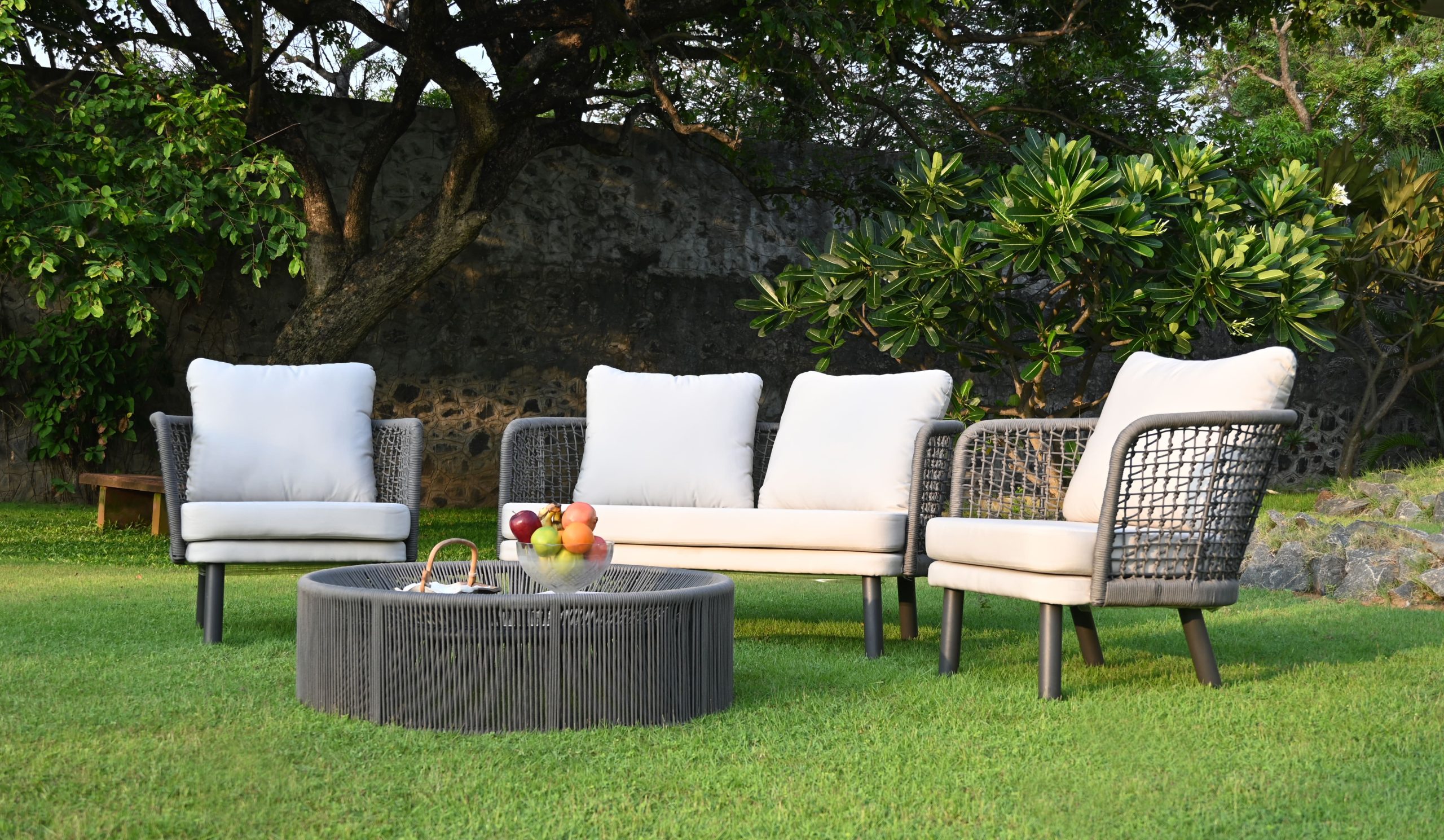 Monsoon outdoor furniture set with cushioned sofa, chairs, and round table on garden lawn.