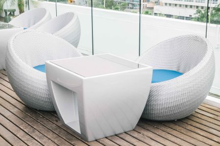 Modern white wicker outdoor furniture with round chairs and a square table on a wooden deck in Chennai.