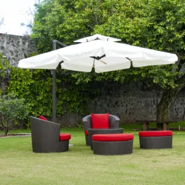 Outdoor furniture in Bangalore garden with wicker chairs, red cushions, and umbrella shade.